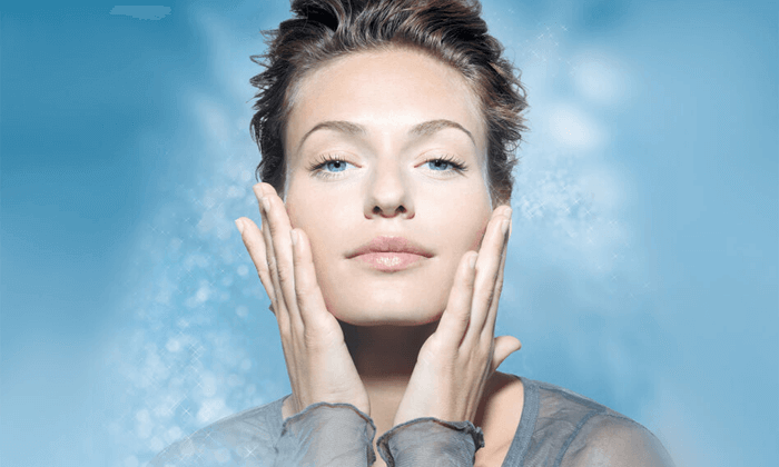 Picture of a woman looking at the camera touching her face with both hands enjoying the texture of her skin after the laser procedure she had done in San José, Costa Rica